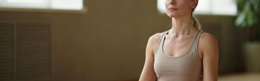 Femme européenne calme assise en méditation dans un intérieur lumineux avec une ambiance apaisante