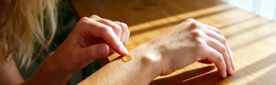 Femme caucasienne appliquant une huile essentielle sur son poignet dans une lumière naturelle, peau aux tons chauds