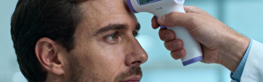Médecin européen mesurant la température d'un patient avec un thermomètre digital sur le front