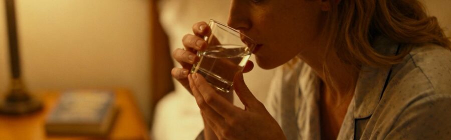 Femme européenne prenant un complément alimentaire pour le sommeil dans son lit avec éclairage doux et chaleureux